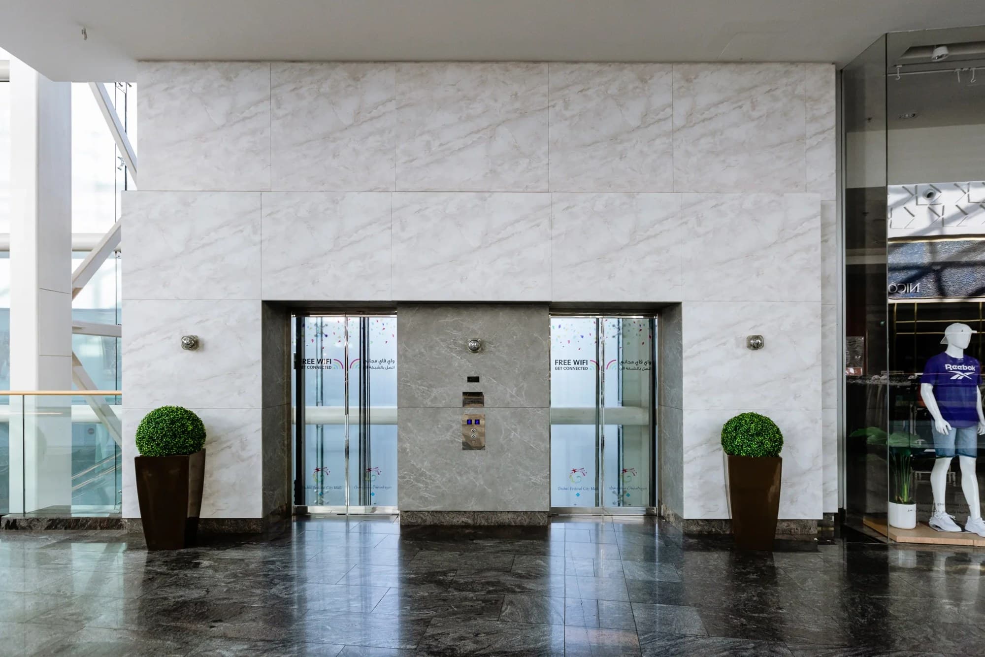 Façade d’ascenseur habillée en marbre blanc dans un centre commercial